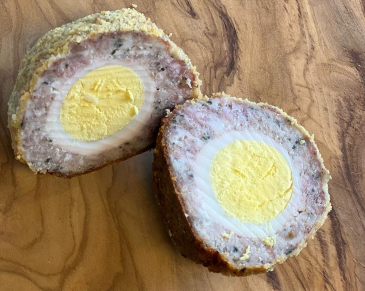 Hard boiled egg encased in Cumberland sausage meat, rolled in fine breadcrumbs and baked to perfection, cut in half